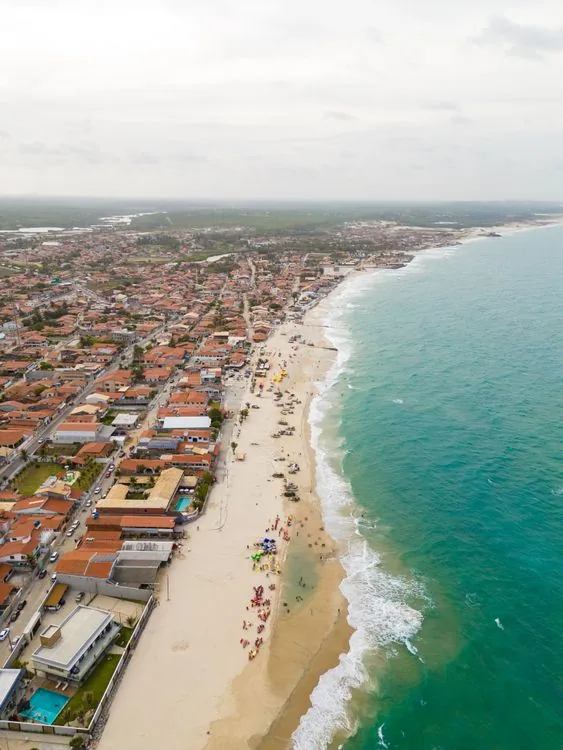 Aerial view of a busy coastal beachfront in Fortaleza with turquoise water and a bright urban skyline.