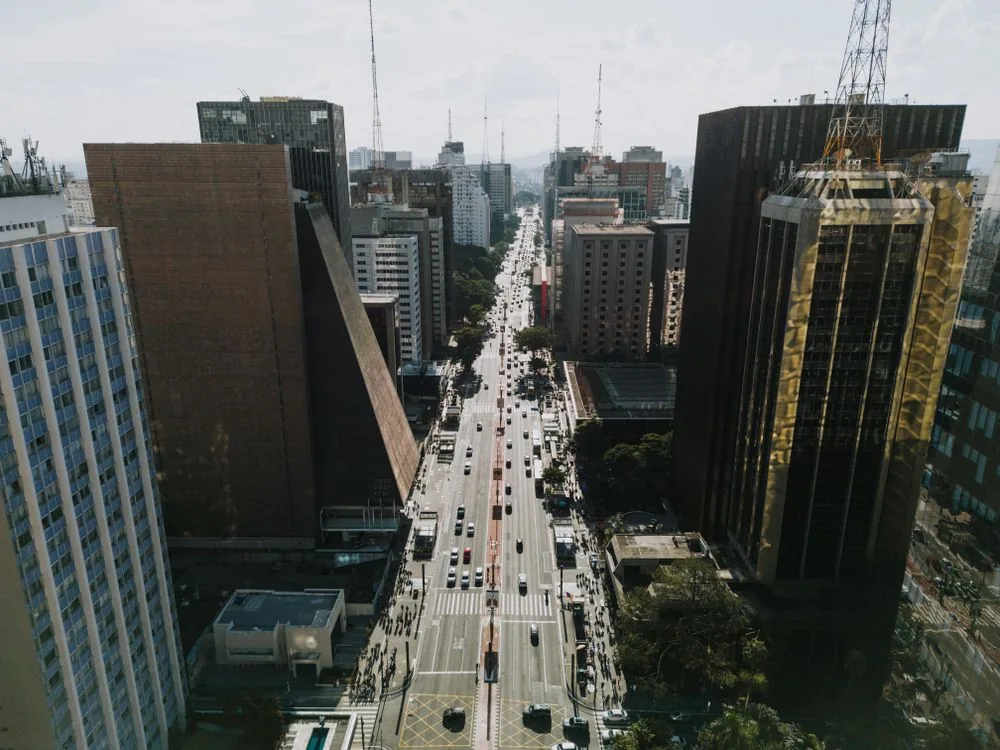 Avenida urbana concurrida en São Paulo entre edificios altos.
