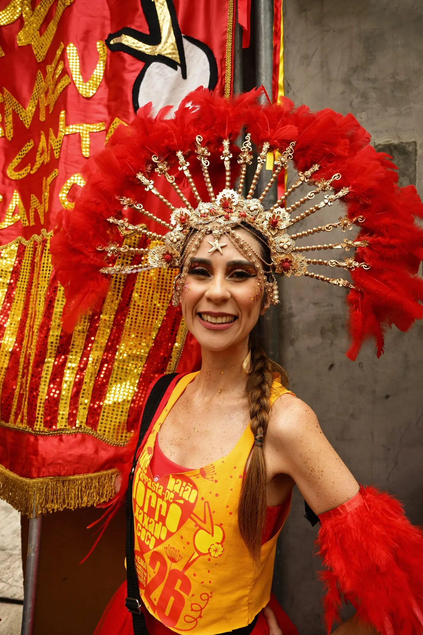 Bailarina de Carnaval con un vibrante traje de plumas sonriendo durante una celebración festiva al aire libre.