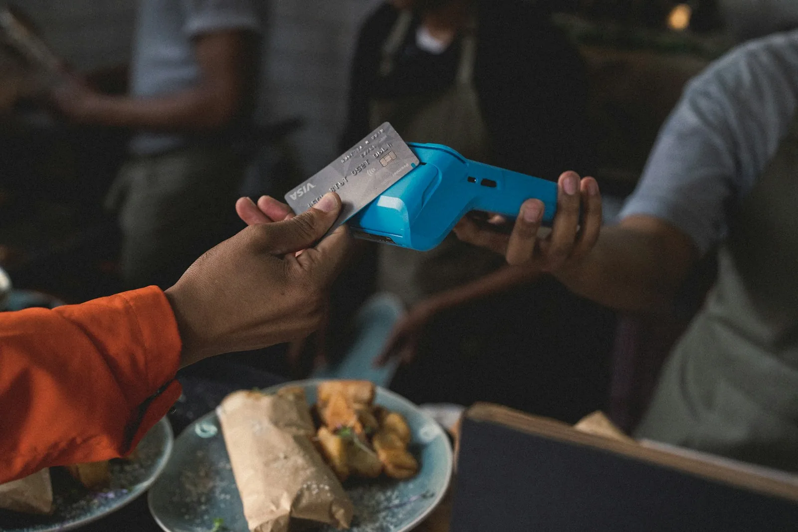Primer plano de una persona acercando una tarjeta a un datáfono: el momento exacto en que ocurre la estafa del cambio de máquina en restaurantes y tiendas de Brasil.