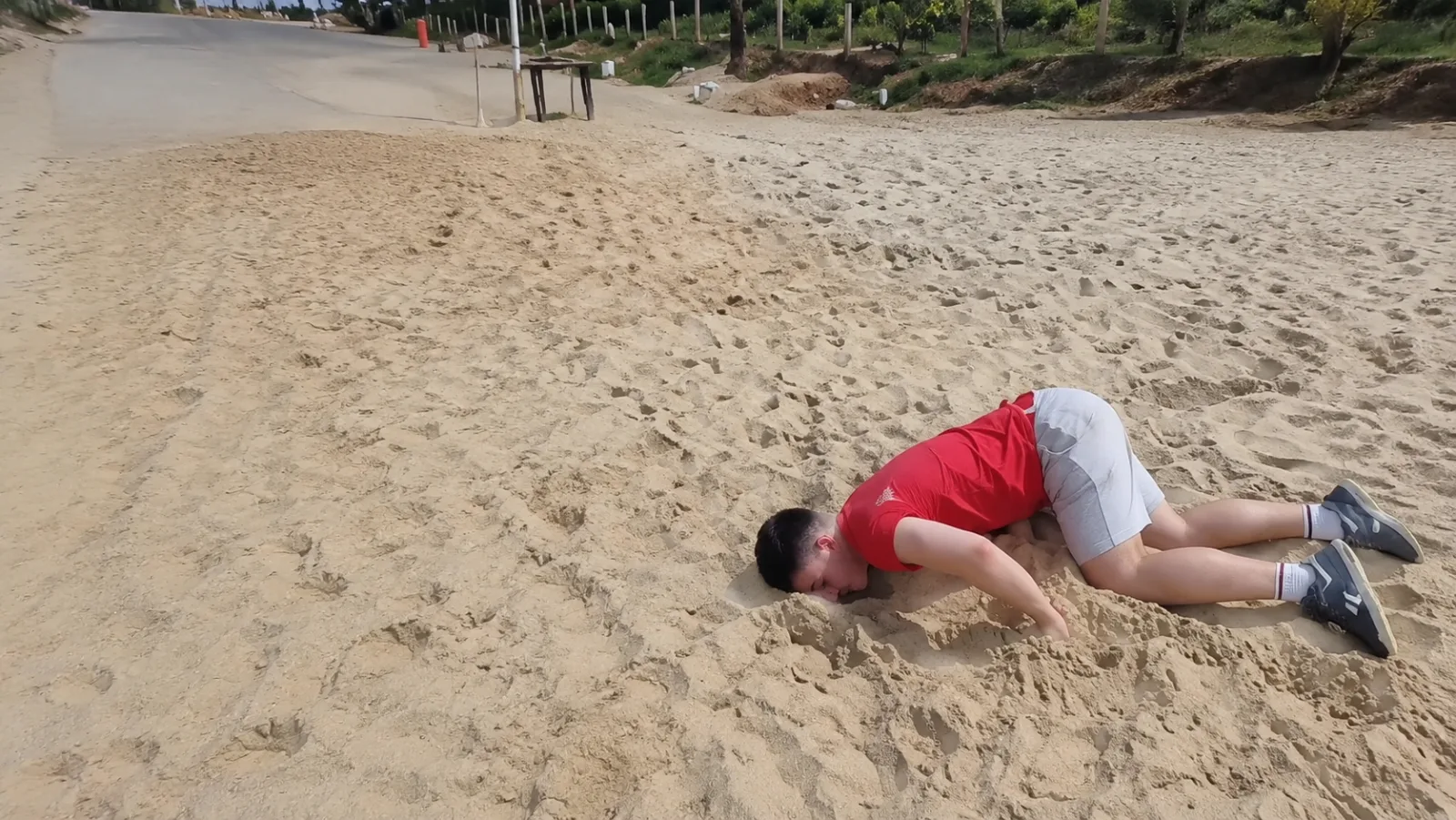 A man lying unconscious on sand.