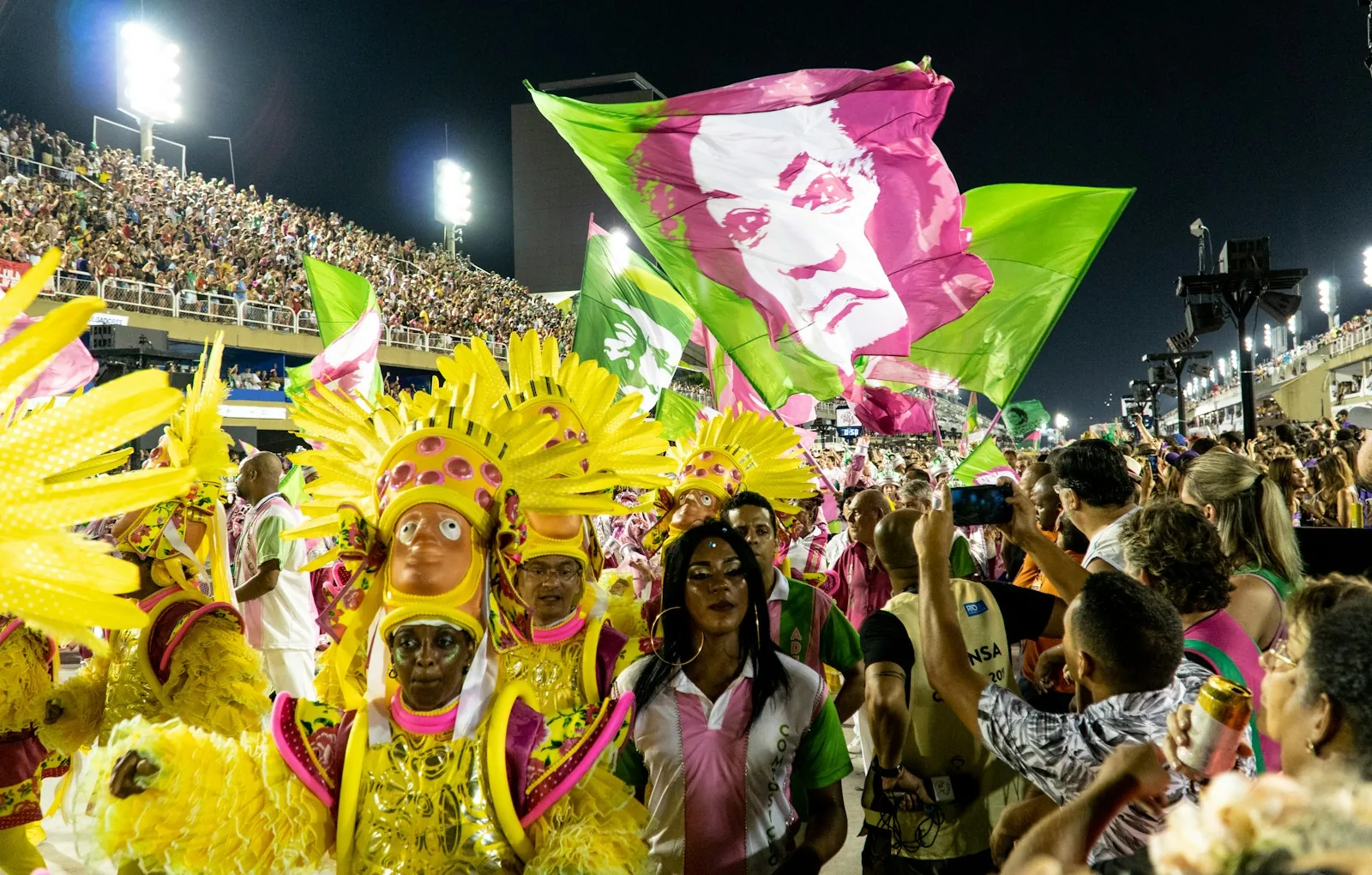 Masked carnival crowd waving flags during a street celebration