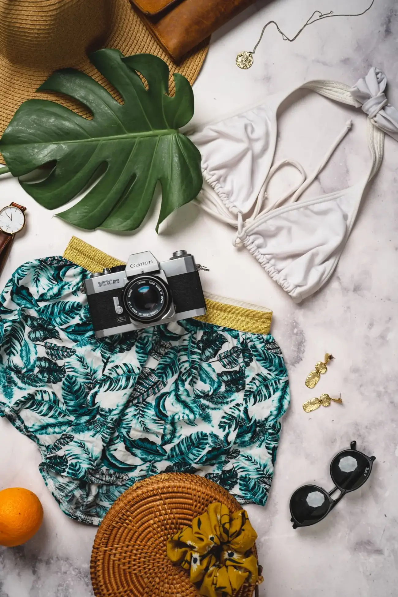 Summer clothing, swimwear and travel accessories laid out — the packing decisions this guide covers by season and city.