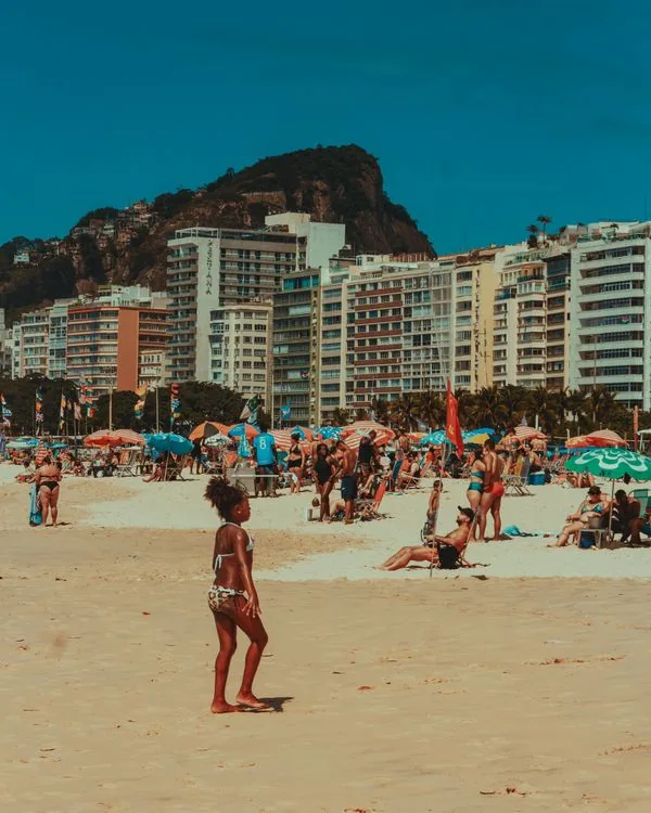 Copacabana beach in Rio de Janeiro packed with people on a sunny day; hotels and apartments in this area run on Type N outlets at 127V.