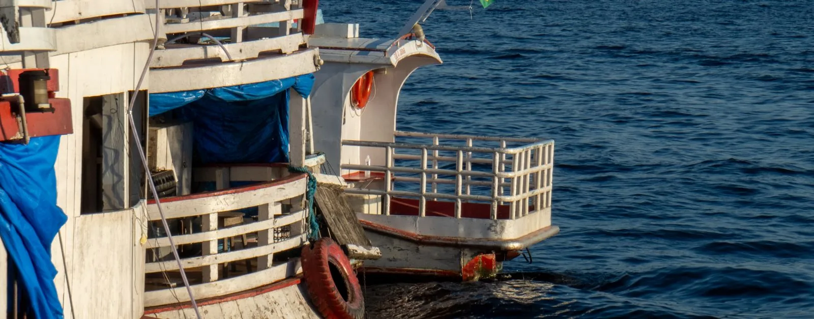 Traditional wooden boats moored on the Amazon River in Manaus during the day.