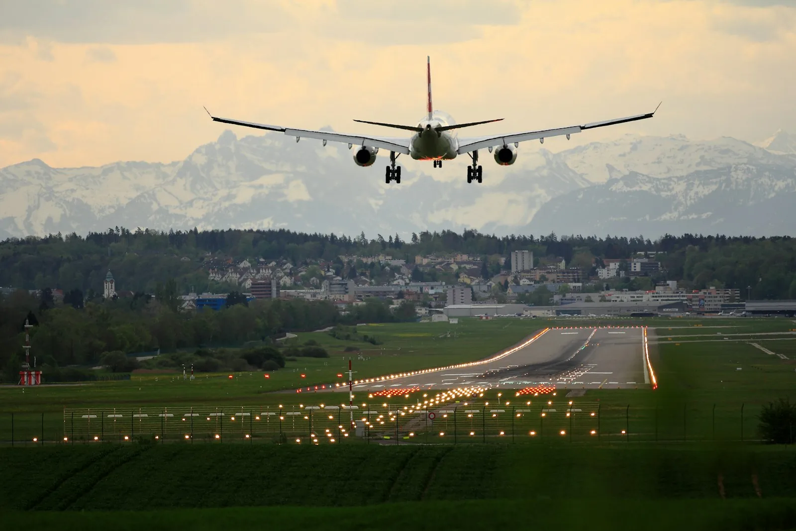 White airplane on an airport runway with mountains in the distance, illustrating airport arrival and aviation logistics.